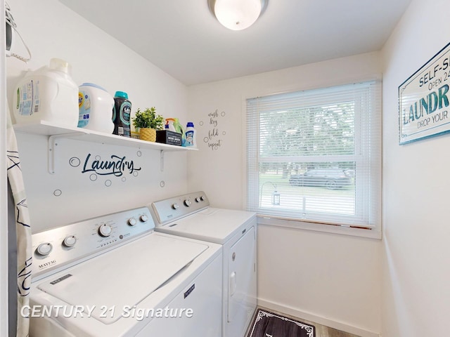 laundry area featuring washing machine and dryer, healthy amount of natural light, and baseboards