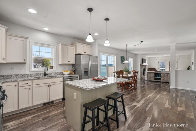 kitchen with stainless steel appliances, a sink, dark wood-style floors, light stone counters, and recessed lighting