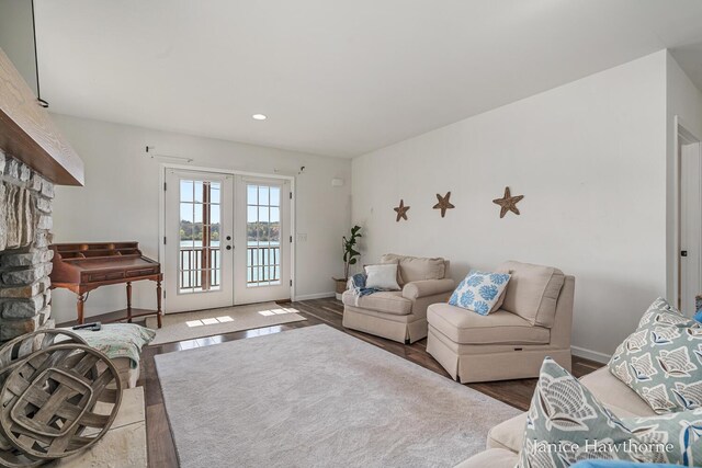living room featuring french doors, wood finished floors, baseboards, recessed lighting, and a water view