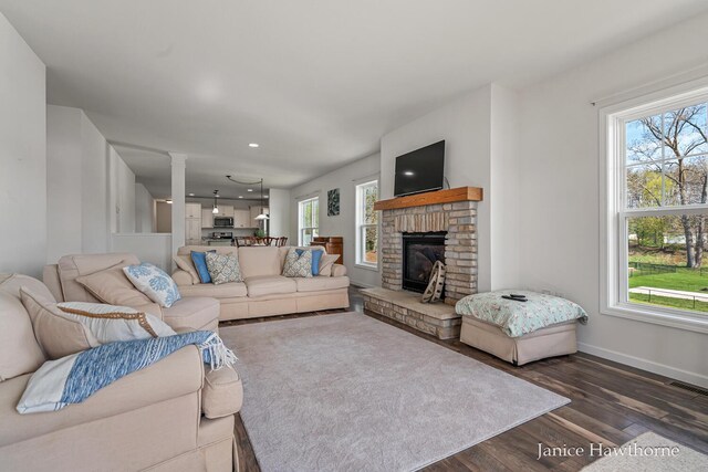 living room featuring wood finished floors, ornate columns, baseboards, a brick fireplace, and recessed lighting