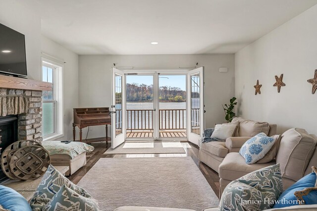 living area featuring wood finished floors, a water view, recessed lighting, and a fireplace