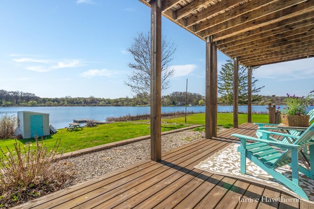 wooden terrace featuring a water view and a yard