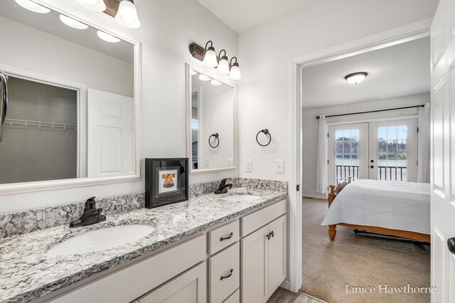 full bathroom featuring french doors, double vanity, a water view, and ensuite bath