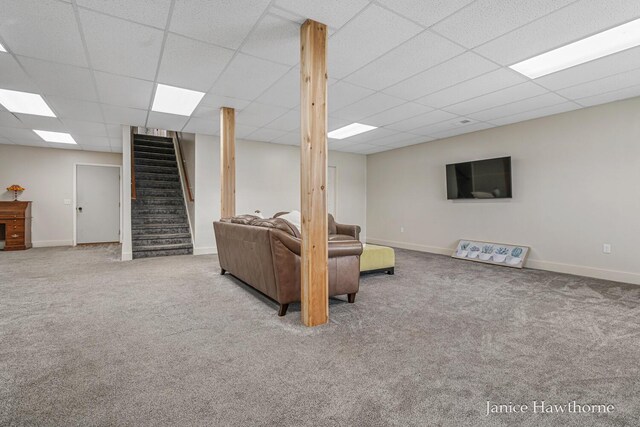 carpeted living room with stairs, a drop ceiling, and baseboards