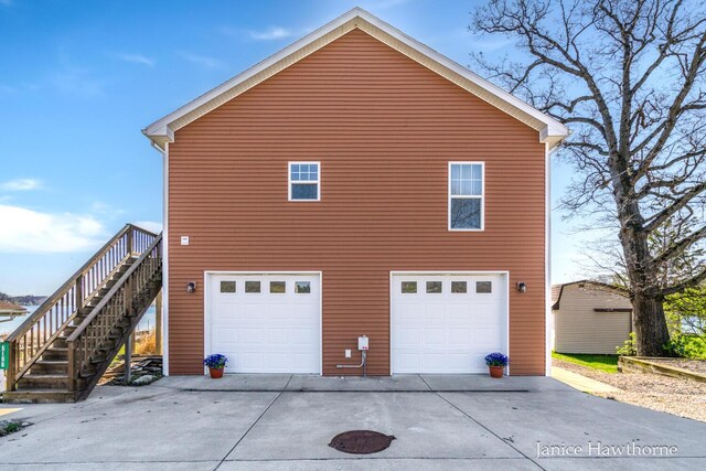 view of home's exterior featuring a garage, concrete driveway, and stairway