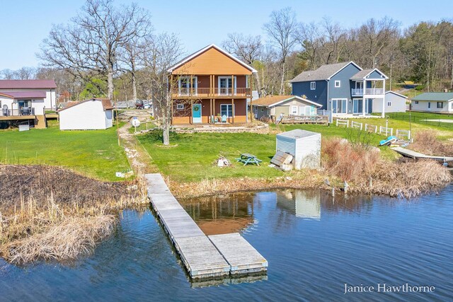 rear view of property featuring a water view, a lawn, and an outdoor structure