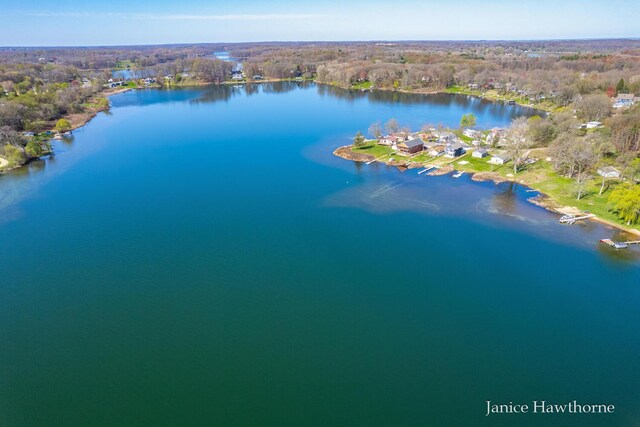view of property location with a nearby body of water and a heavily wooded area