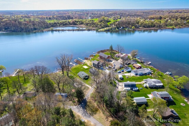 aerial view of property's location with a forest, a nearby body of water, and nearby suburban area