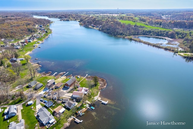 view of property location with a large body of water, a forest, and nearby suburban area