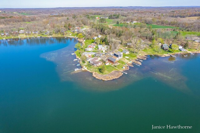 aerial view of property's location featuring a nearby body of water and a heavily wooded area
