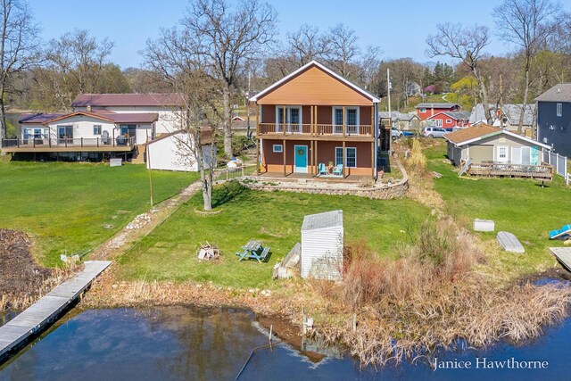 back of property with a deck with water view, a yard, a residential view, and a patio area
