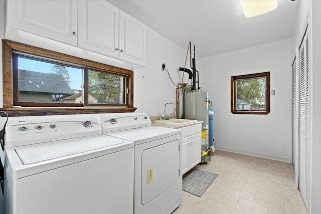 laundry room with washer and clothes dryer, cabinet space, water heater, and healthy amount of natural light