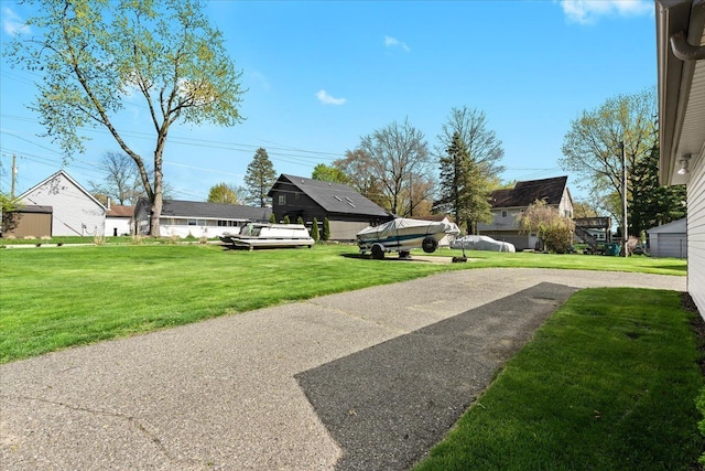 view of grassy yard featuring asphalt driveway