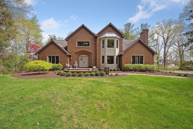 view of front of house with a chimney, brick siding, and a front lawn