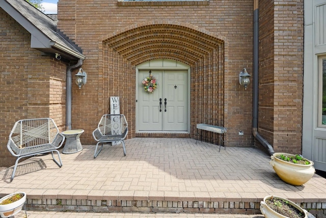 property entrance featuring brick siding and a patio