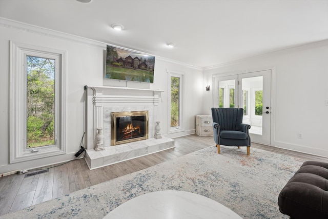living room with crown molding, wood finished floors, a high end fireplace, and baseboards