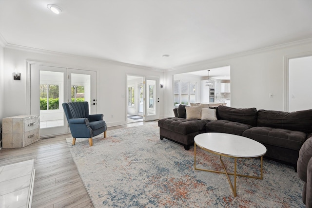 living room featuring healthy amount of natural light, crown molding, and light wood-style floors
