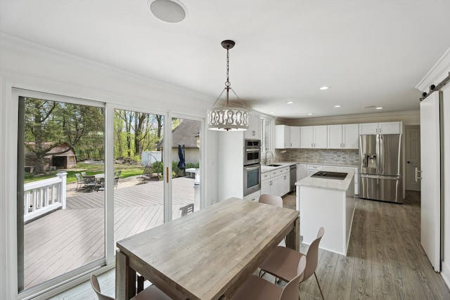 dining space featuring crown molding, a barn door, wood finished floors, a chandelier, and recessed lighting