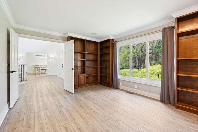 spare room featuring crown molding, light wood-type flooring, baseboards, and a chandelier
