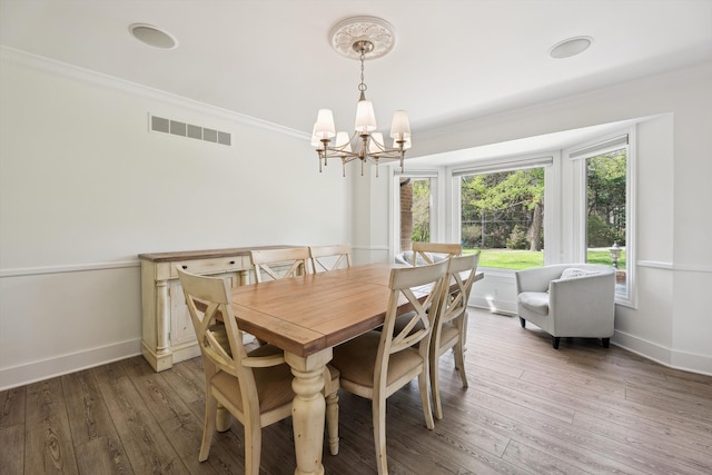 dining area featuring a chandelier, ornamental molding, hardwood / wood-style flooring, and baseboards