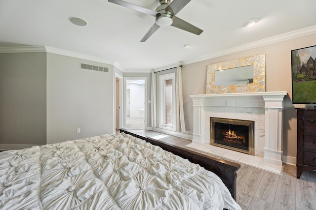 bedroom featuring crown molding, a tile fireplace, wood finished floors, and ceiling fan