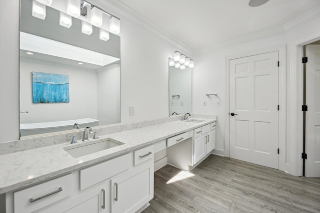 full bathroom with wood finished floors, crown molding, double vanity, and a tub