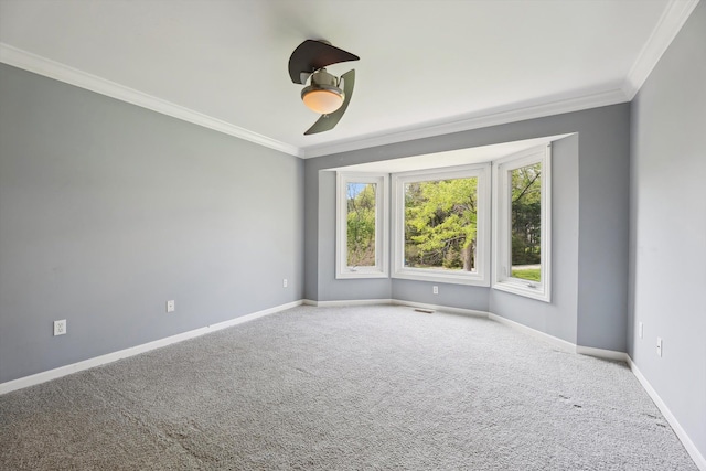 carpeted spare room featuring ornamental molding, plenty of natural light, a ceiling fan, and baseboards