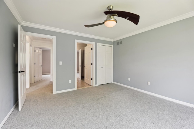 unfurnished bedroom featuring crown molding, light carpet, baseboards, ceiling fan, and a closet