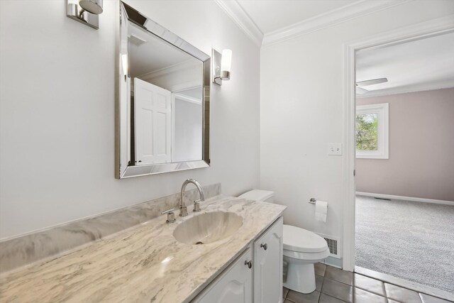 bathroom with toilet, crown molding, vanity, tile patterned floors, and baseboards