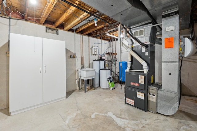 unfinished below grade area with a water pressure tank, concrete block wall, a water softener system, a sink, and heating unit