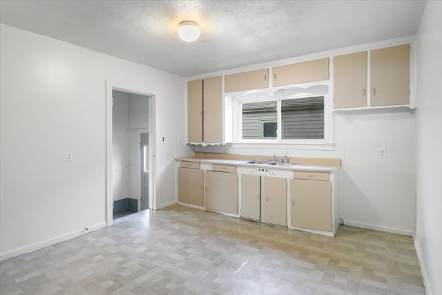 12855 Couwlier Ave, Warren, MI 48089 - kitchen featuring a sink, light countertops, baseboards, cream cabinetry, and a textured ceiling
