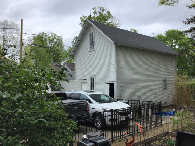 view of side of property featuring fence and a shingled roof