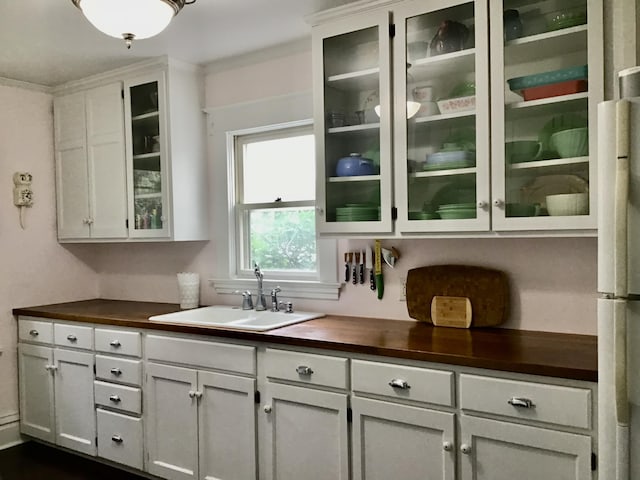 bar area with a sink, ornamental molding, and freestanding refrigerator