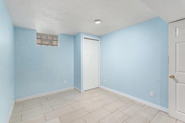 finished basement with baseboards and a textured ceiling