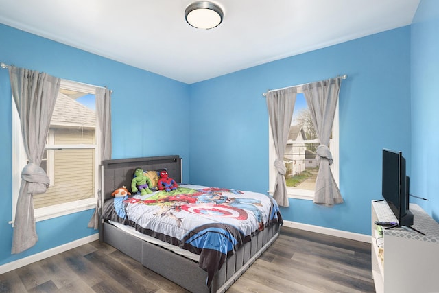 bedroom with multiple windows, baseboards, and wood finished floors