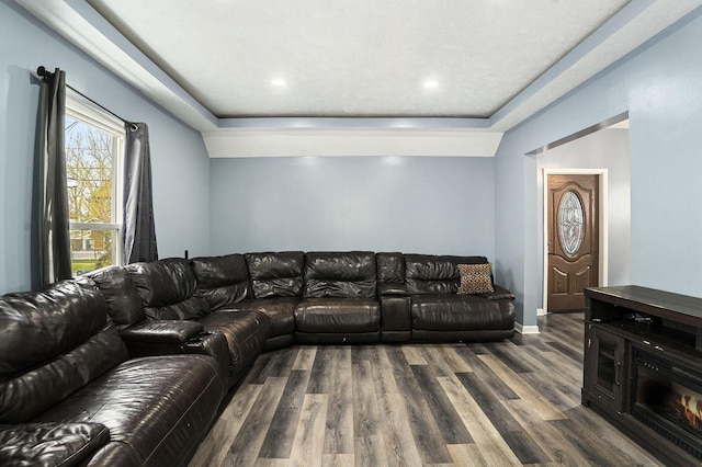 living room featuring a raised ceiling, wood finished floors, baseboards, and recessed lighting