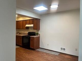 23004 Doremus St Unit 2, Saint Clair Shores, MI 48080 - kitchen featuring black range with electric cooktop, under cabinet range hood, wood finished floors, and light countertops