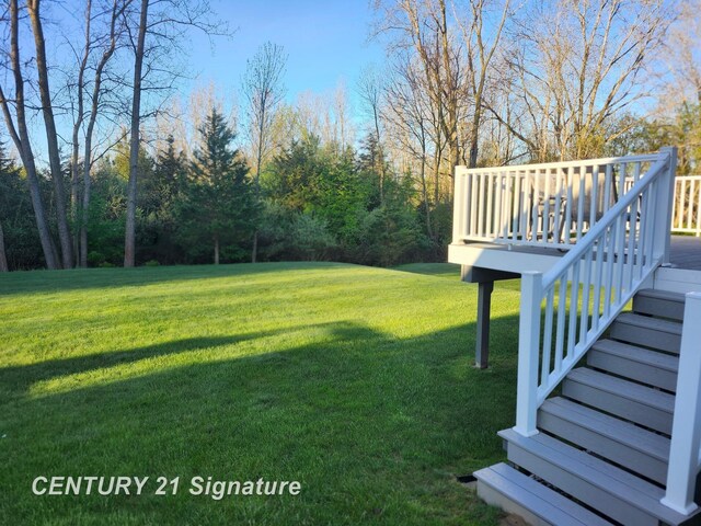 view of grassy yard with stairs and a deck