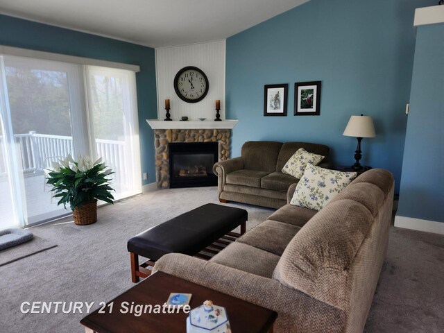living room featuring carpet, baseboards, and a stone fireplace