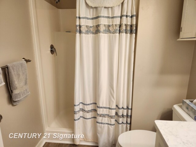full bath with toilet, a stall shower, vanity, and baseboards