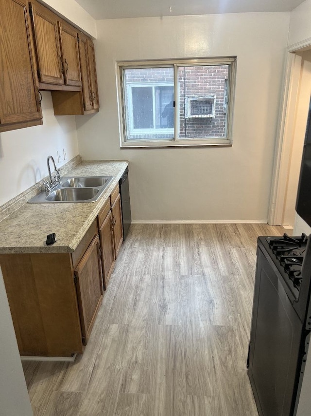 kitchen with a sink, dishwasher, light wood-style floors, range with gas stovetop, and light countertops