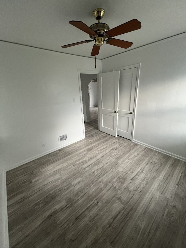 unfurnished bedroom with wood finished floors, a ceiling fan, and baseboards