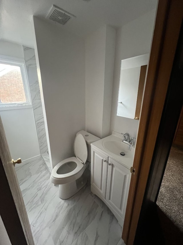 full bath with marble finish floors, toilet, vanity, and a shower stall