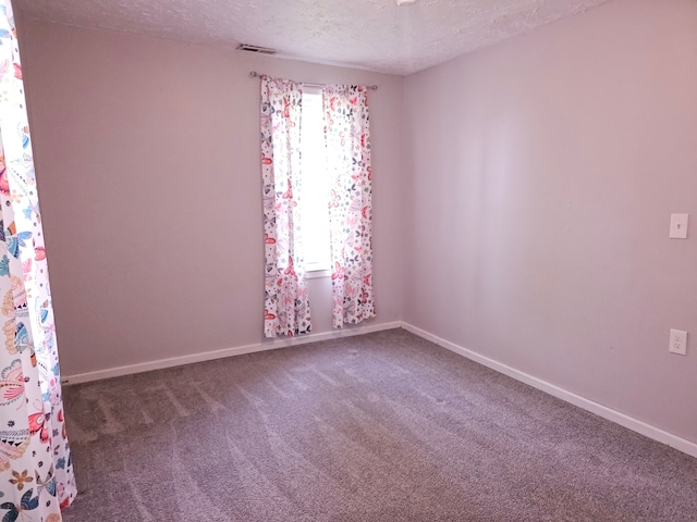 spare room featuring a textured ceiling, carpet floors, and baseboards