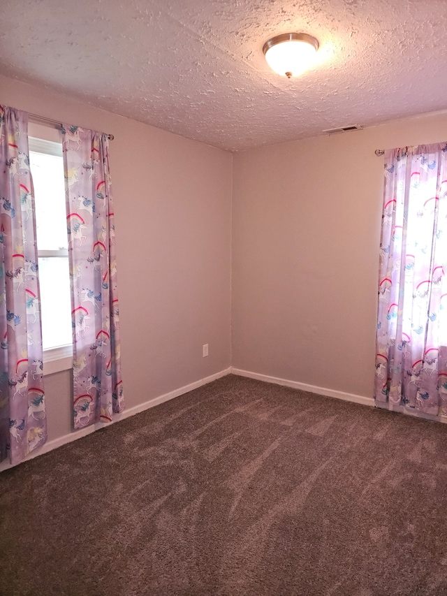 spare room featuring a textured ceiling, carpet, and baseboards