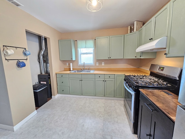 kitchen with stainless steel range with gas cooktop, a sink, green cabinets, under cabinet range hood, and wooden counters