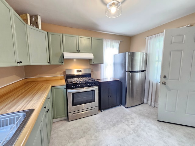 kitchen featuring stainless steel appliances, under cabinet range hood, green cabinets, a sink, and light countertops