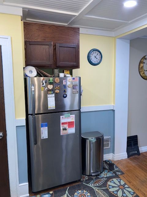 kitchen with freestanding refrigerator, wood finished floors, baseboards, and dark brown cabinets