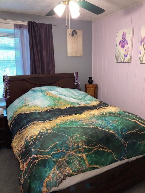 carpeted bedroom with a textured ceiling and a ceiling fan