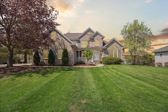 view of front of home featuring a front lawn, brick siding, and covered porch